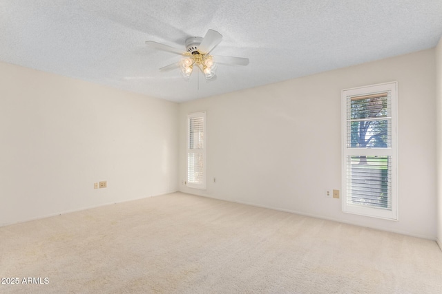 spare room with a ceiling fan, light carpet, and a textured ceiling