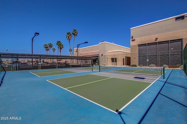 view of tennis court with community basketball court and fence