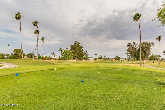 view of community featuring view of golf course and a yard