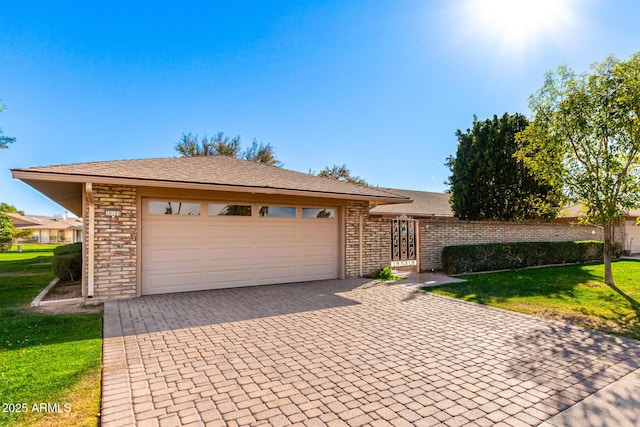 single story home featuring an attached garage, a front lawn, decorative driveway, and brick siding