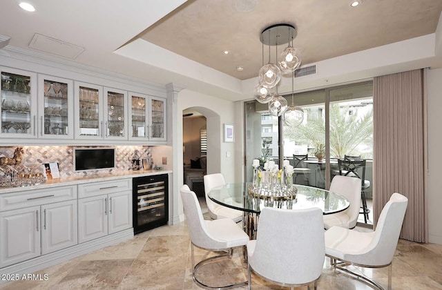 dining area with visible vents, beverage cooler, recessed lighting, arched walkways, and a raised ceiling