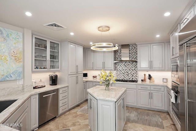 kitchen with visible vents, tasteful backsplash, appliances with stainless steel finishes, wall chimney range hood, and glass insert cabinets