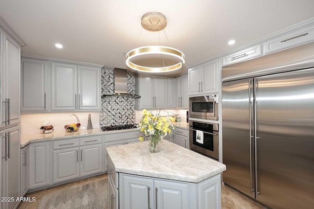 kitchen featuring built in appliances, backsplash, a kitchen island, and wall chimney exhaust hood