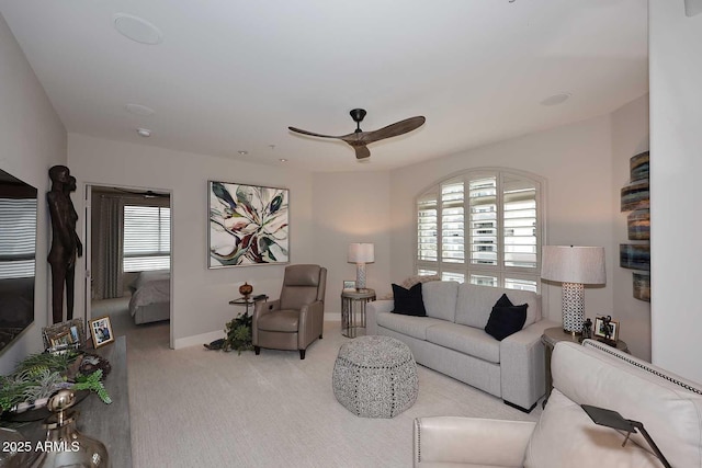 living area featuring baseboards, ceiling fan, and carpet floors