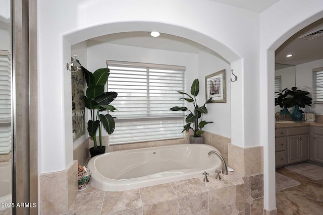 bathroom with visible vents, vanity, and a garden tub