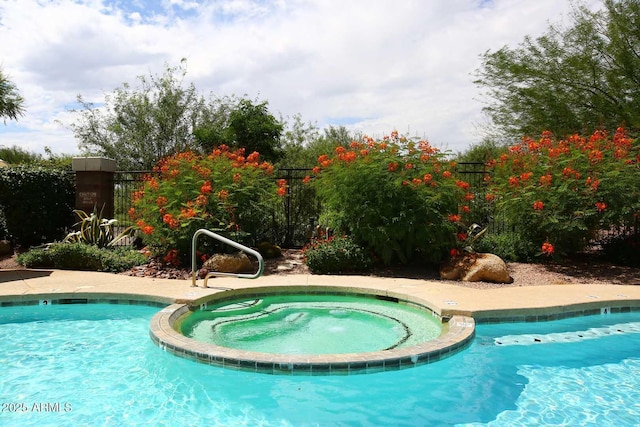 view of pool with fence and a pool with connected hot tub