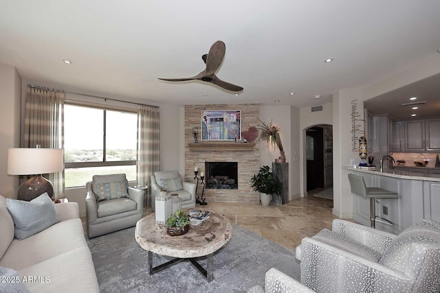 living room featuring arched walkways, recessed lighting, a fireplace, and a ceiling fan