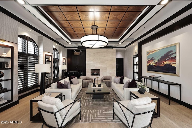 interior space featuring a fireplace, baseboards, light wood-style floors, and a tray ceiling