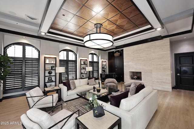 living area with a raised ceiling, light wood-style flooring, visible vents, and coffered ceiling