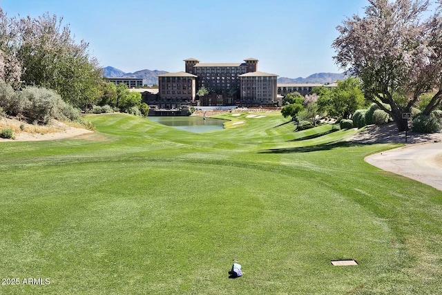 view of home's community with a water and mountain view, golf course view, and a yard