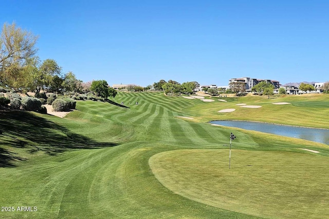 view of property's community with view of golf course, a yard, and a water view