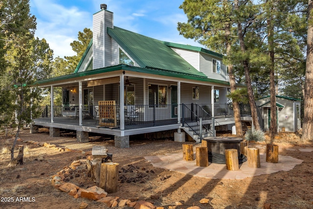 back of house with ceiling fan, a chimney, metal roof, an outdoor structure, and a porch