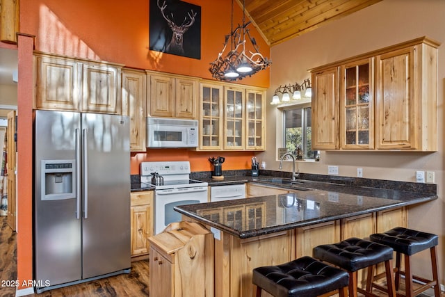 kitchen with wooden ceiling, a sink, dark stone counters, white appliances, and a peninsula