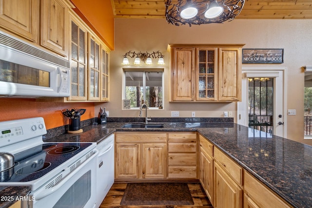 kitchen featuring wooden ceiling, glass insert cabinets, a sink, dark stone counters, and white appliances