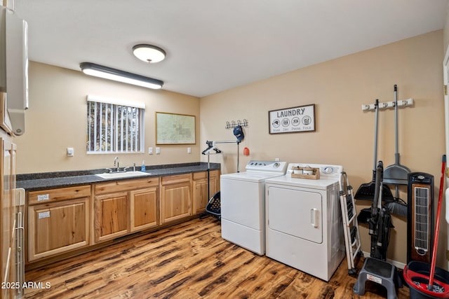 laundry room featuring light wood-type flooring, cabinet space, washer and dryer, and a sink