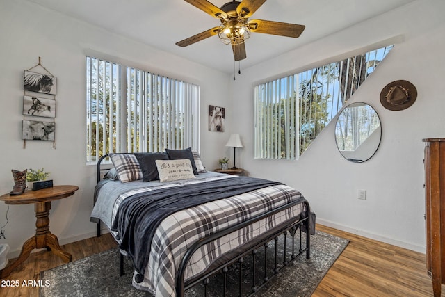 bedroom featuring a ceiling fan, baseboards, and wood finished floors