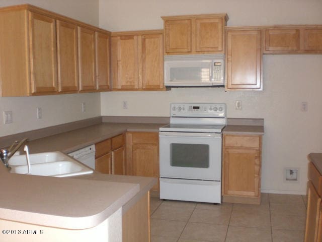 1412 E Oakland St, Gilbert, AZ 85295 - kitchen featuring white appliances, a sink, a peninsula, light tile patterned flooring, and light countertops