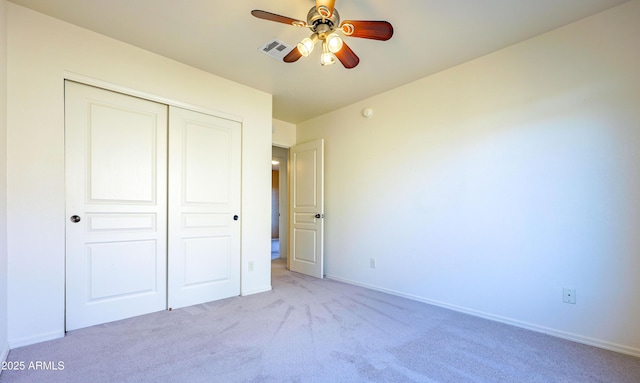 unfurnished bedroom featuring light carpet, ceiling fan, and a closet