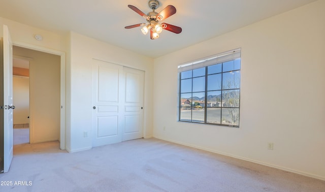 unfurnished bedroom featuring light carpet, ceiling fan, and a closet