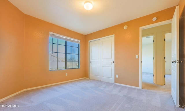 unfurnished bedroom featuring light carpet and a closet