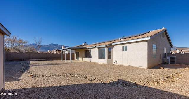 back of property featuring a mountain view, a patio area, central air condition unit, and solar panels