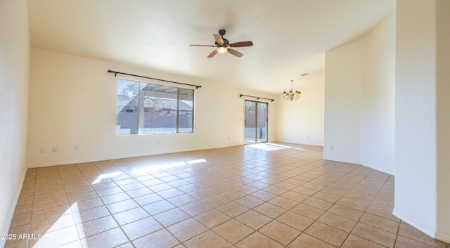 tiled spare room with ceiling fan with notable chandelier