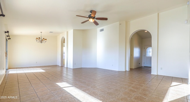 tiled empty room featuring ceiling fan with notable chandelier