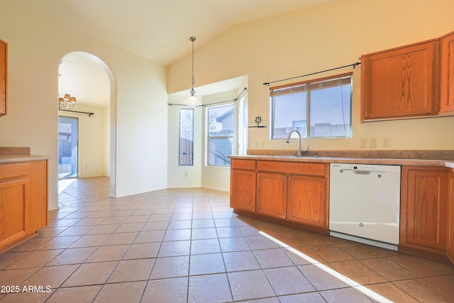 kitchen featuring sink, vaulted ceiling, hanging light fixtures, light tile patterned floors, and white dishwasher