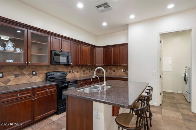 43998 W Palo Abeto Dr, Maricopa, AZ 85138 - kitchen featuring visible vents, a sink, black appliances, washer / dryer, and a breakfast bar
