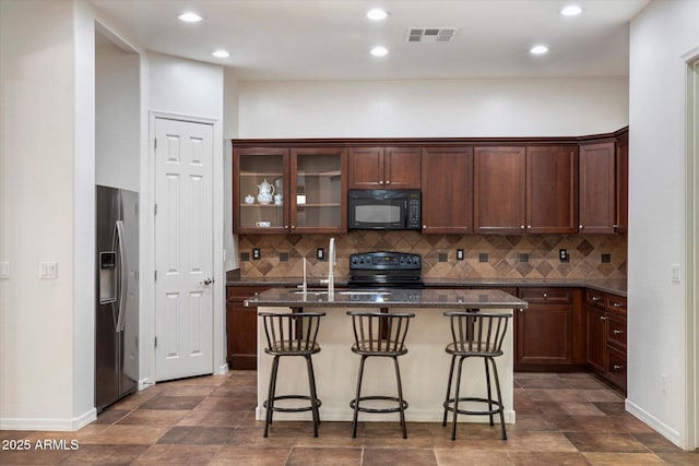 43998 W Palo Abeto Dr, Maricopa, AZ 85138 - kitchen featuring visible vents, decorative backsplash, black appliances, and a kitchen bar