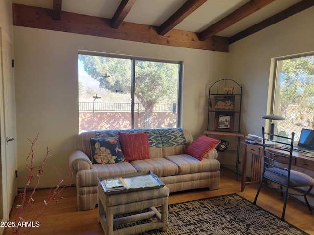 living room with a healthy amount of sunlight, hardwood / wood-style floors, and vaulted ceiling with beams