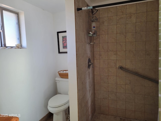 bathroom featuring tiled shower and toilet