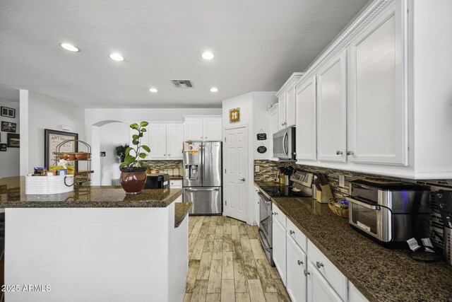 43650 W Snow Dr, Maricopa, AZ 85138 - kitchen featuring stainless steel appliances, arched walkways, light wood finished floors, visible vents, and white cabinets