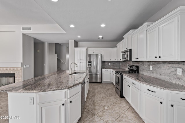 kitchen featuring white cabinets, stainless steel appliances, visible vents, a sink, and decorative backsplash