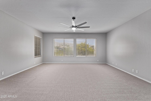 carpeted spare room featuring a ceiling fan and baseboards