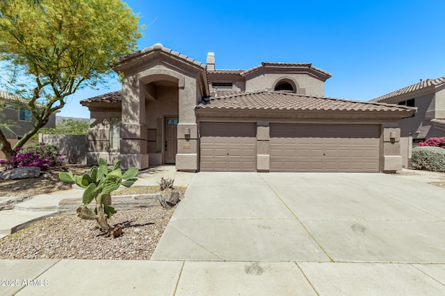 mediterranean / spanish home featuring concrete driveway, a tile roof, stucco siding, and a garage