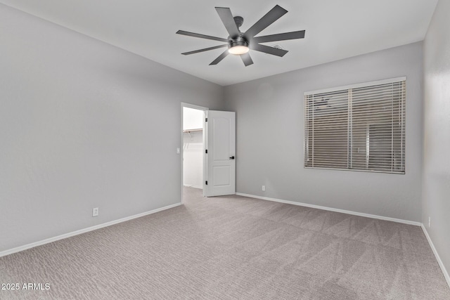 carpeted empty room featuring baseboards and a ceiling fan
