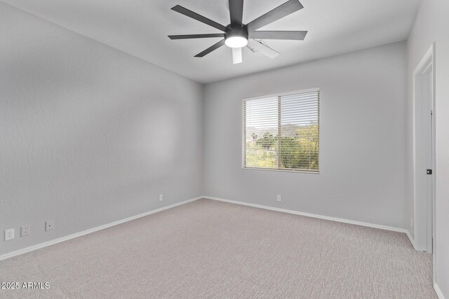 carpeted empty room featuring a ceiling fan and baseboards