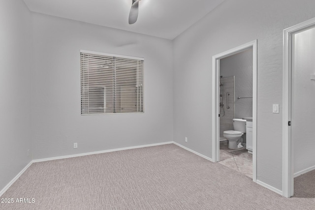 unfurnished bedroom featuring ensuite bath, carpet floors, a ceiling fan, and baseboards