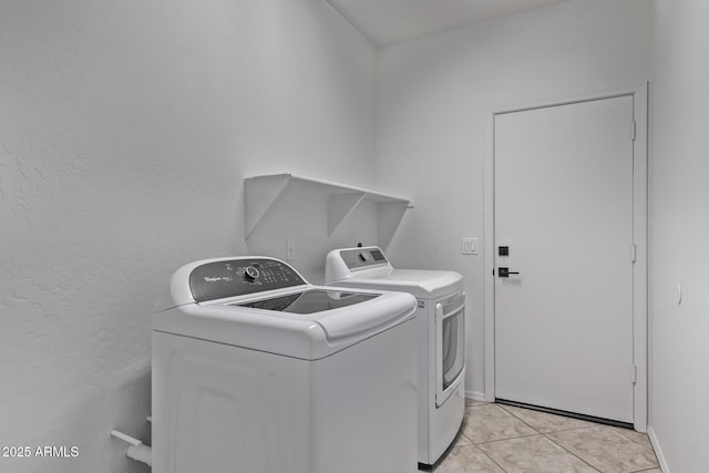 washroom with a textured wall, washer and clothes dryer, laundry area, and light tile patterned floors