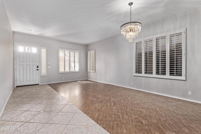 foyer featuring baseboards, a notable chandelier, and tile patterned floors
