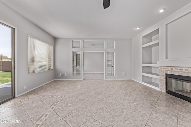 unfurnished living room with built in shelves, a healthy amount of sunlight, tile patterned floors, and a fireplace