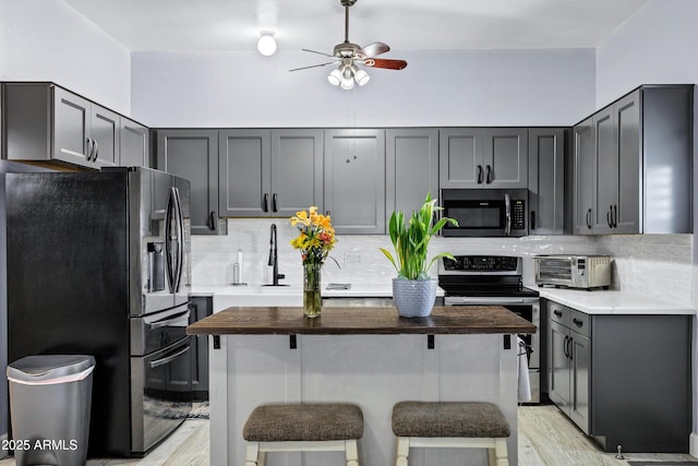 2926 W Smoketree St, Apache Junction, AZ 85120 - kitchen featuring stainless steel appliances, ceiling fan, backsplash, a breakfast bar, and light wood-type flooring