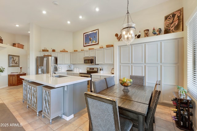 kitchen featuring sink, hanging light fixtures, an island with sink, stainless steel appliances, and backsplash