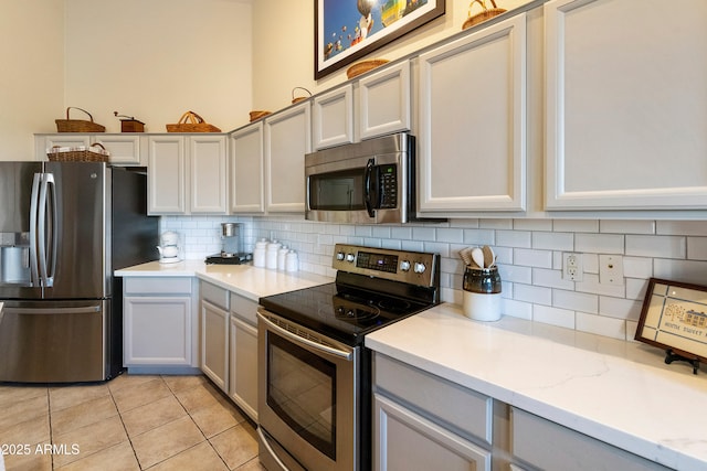 kitchen with light stone counters, backsplash, light tile patterned floors, and stainless steel appliances