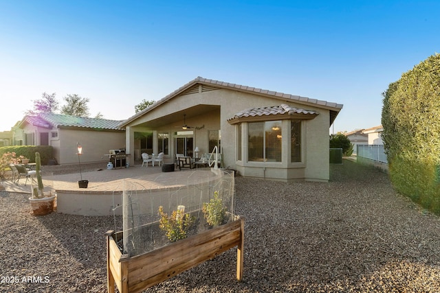 rear view of property featuring ceiling fan and a patio