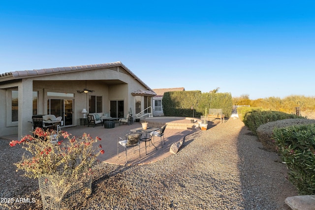 rear view of property featuring a patio, ceiling fan, and an outdoor fire pit