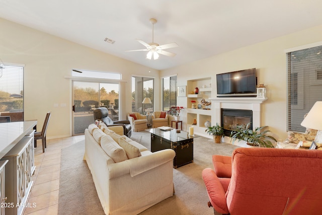 tiled living room featuring vaulted ceiling, ceiling fan, and built in shelves