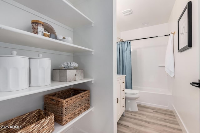 full bathroom featuring vanity, shower / tub combo, hardwood / wood-style flooring, and toilet