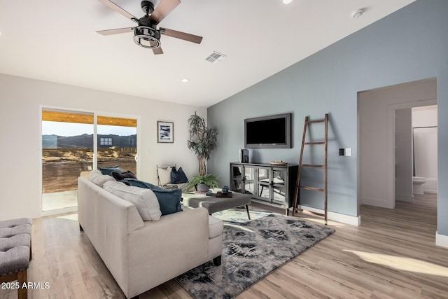 living room with vaulted ceiling, ceiling fan, and light wood-type flooring